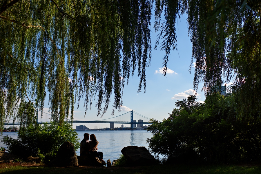 A couple kiss in this silhouette with the ben franklin bridge in the background at penn treaty park.